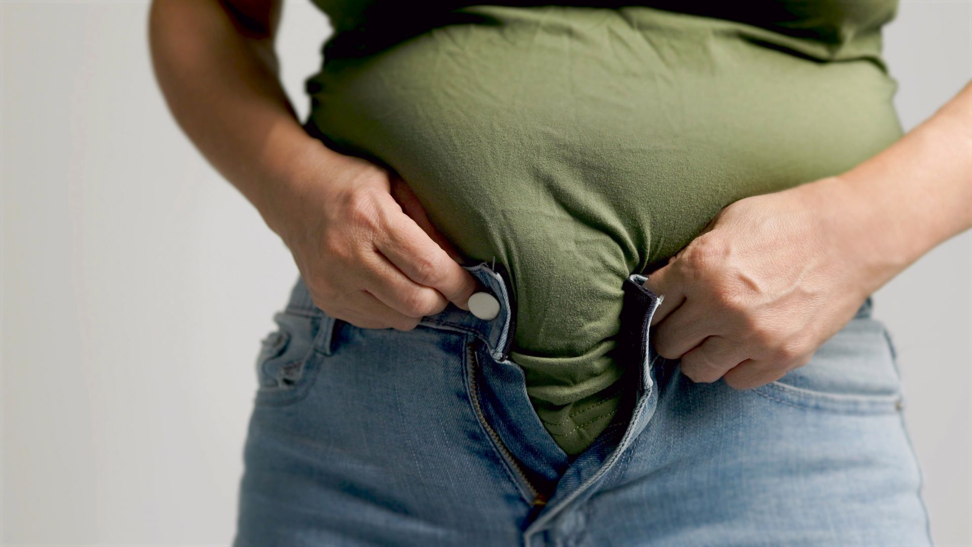 Fat woman zipping up trousers, excess belly fat, unhealthy lifestyle
